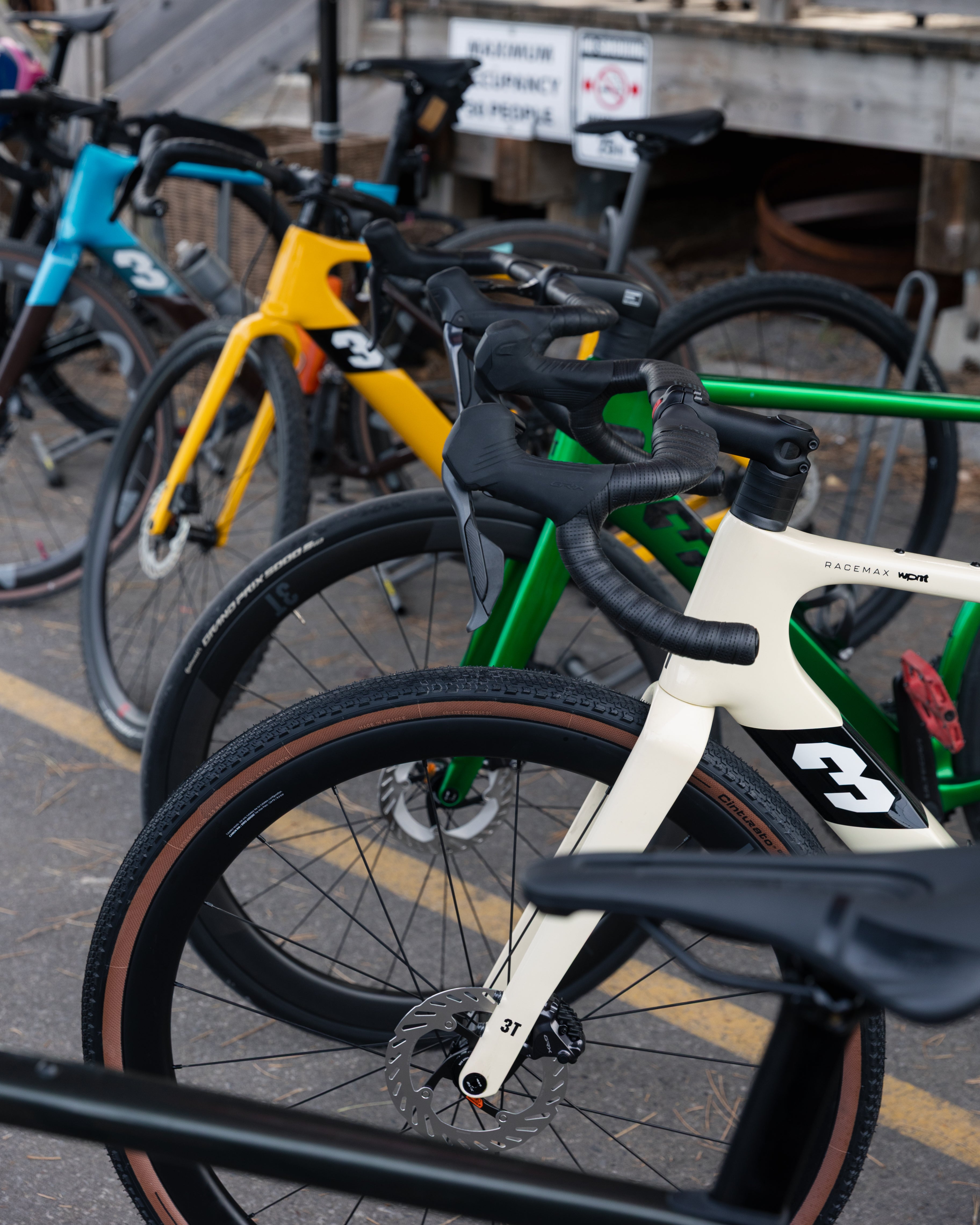 Multiple 3t bicycles parked together on a street with a building in the background