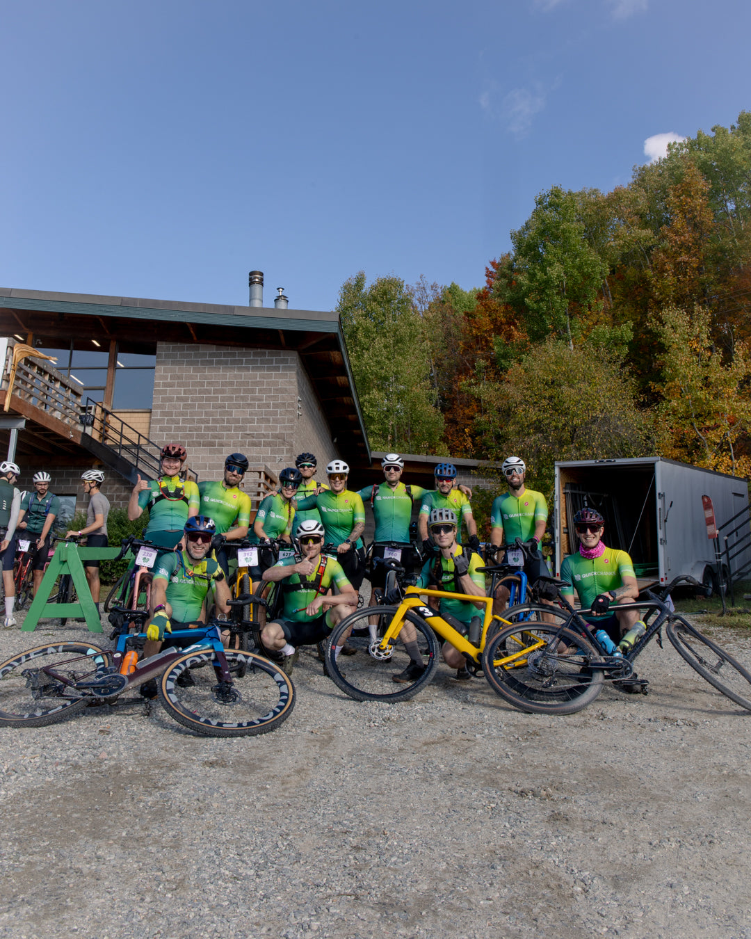 Group of gravel cyclists in quickcranks jerseys posing with their bikes outdoors.