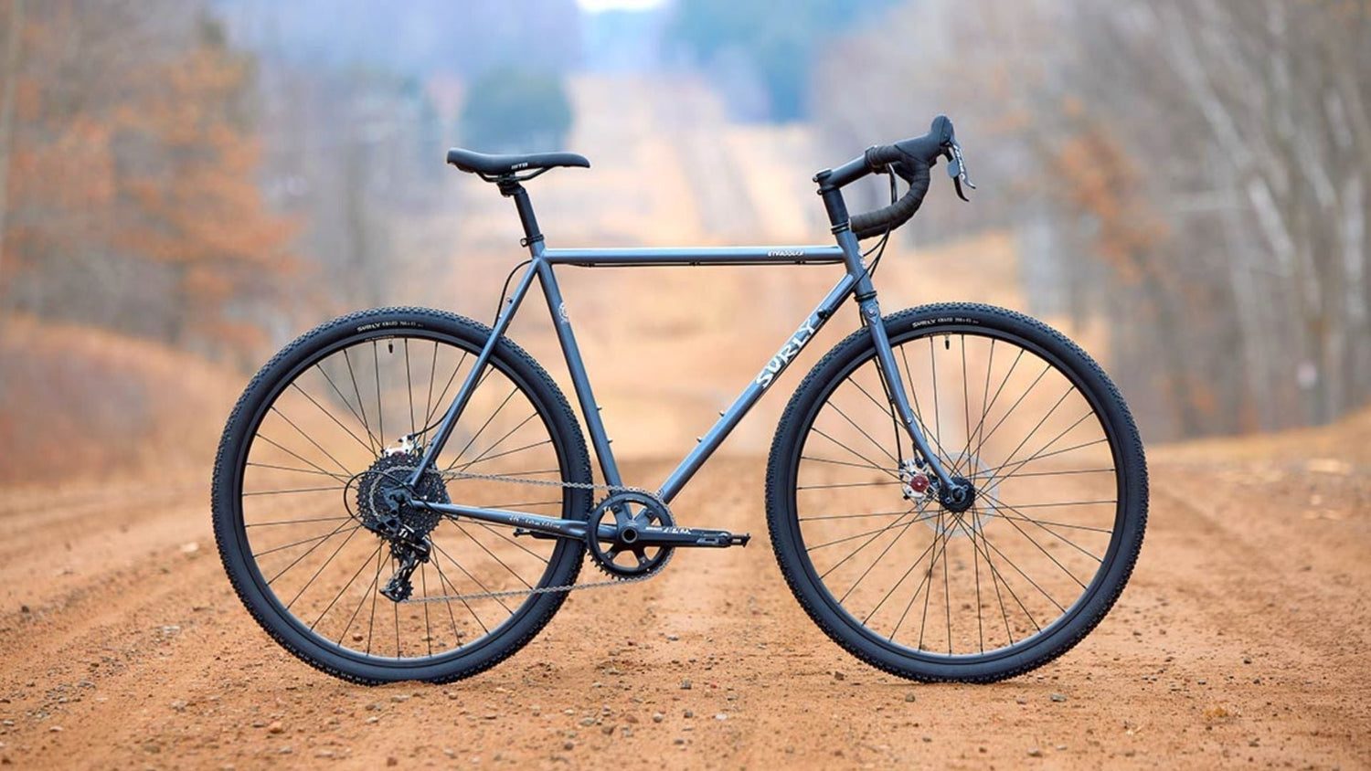 Surly Straggler steel gravel bike on a dirt road showing the versatile drop-bar adventure bike design