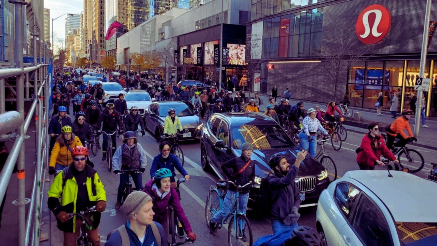Cyclists riding in traffic in a busy city street, illustrating real-world urban cycling and road-sharing in Ontario