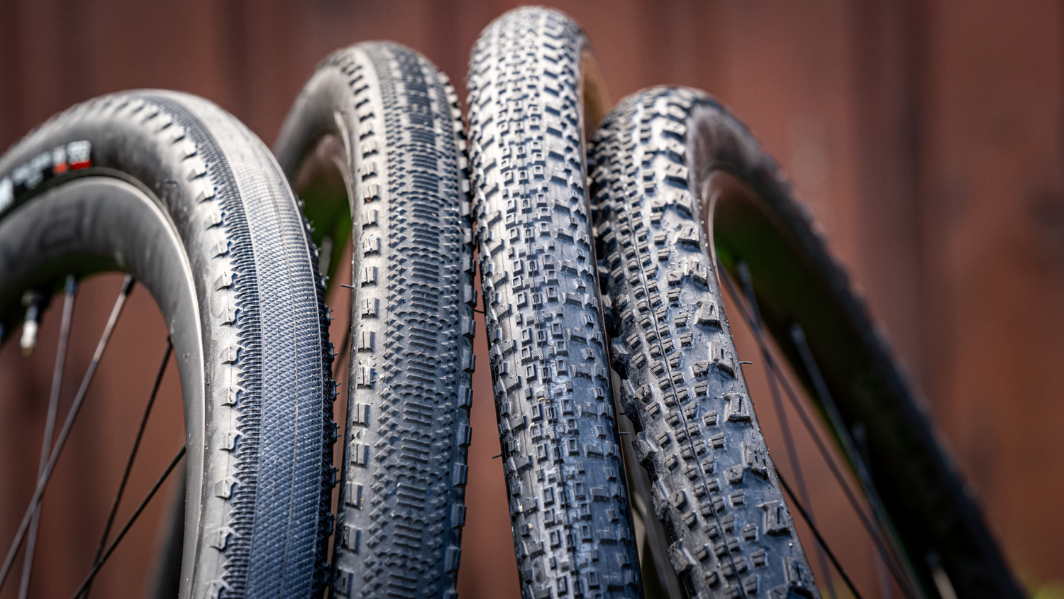 Comparison of different gravel bike tire tread patterns, ranging from slick to aggressive knobs, highlighting tire options for speed, hardpack, mixed terrain, and loose gravel riding.