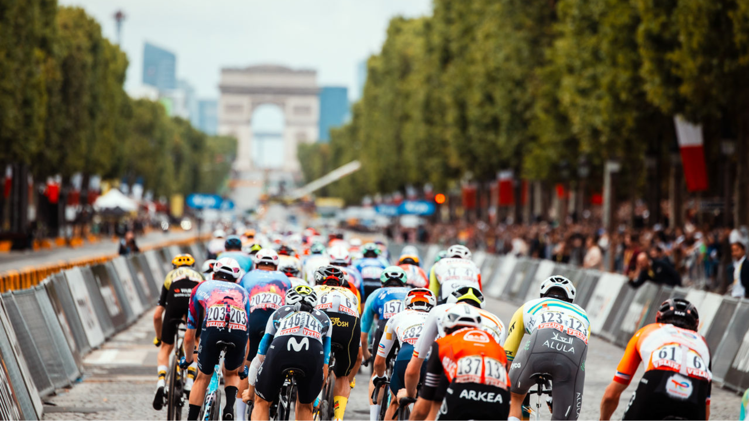 Road cycling race peloton riding through a closed city course with the Arc de Triomphe in the background.