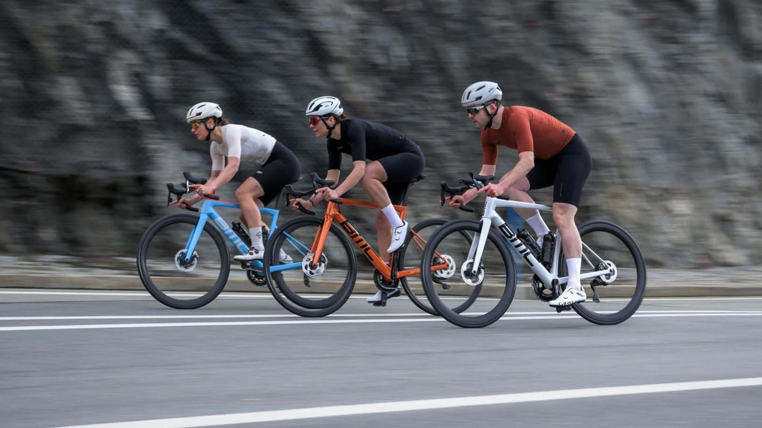 Group of cyclists riding BMC road bikes together on a smooth paved road in a fast-paced training ride